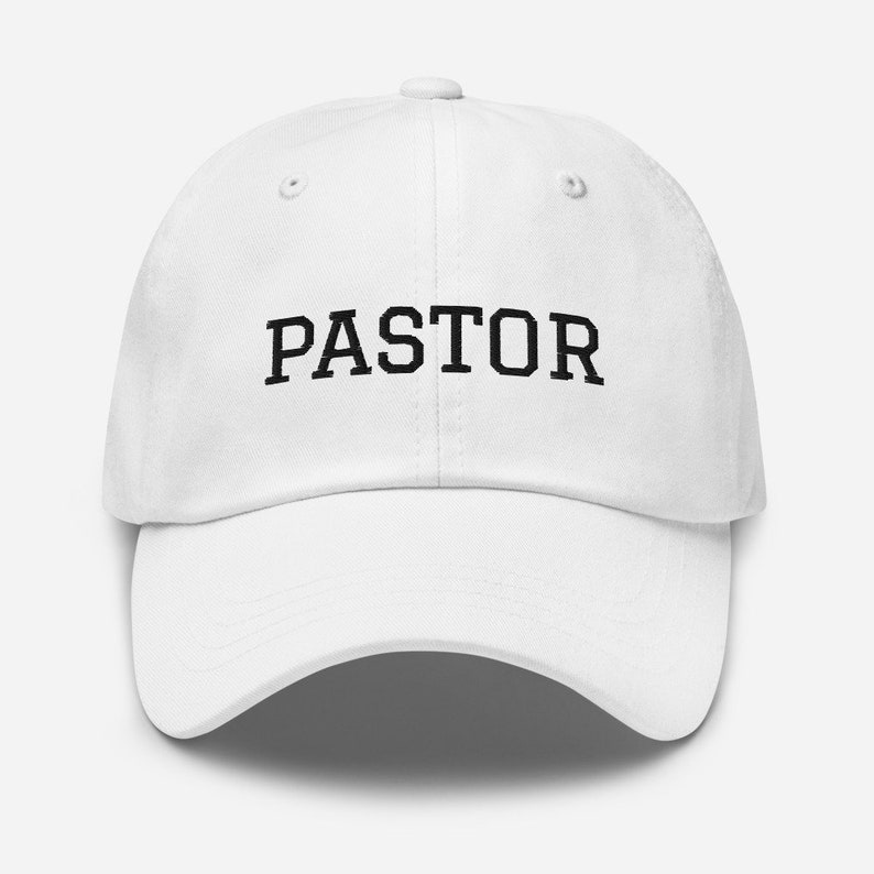May include: White baseball cap with black text that reads "PASTOR".