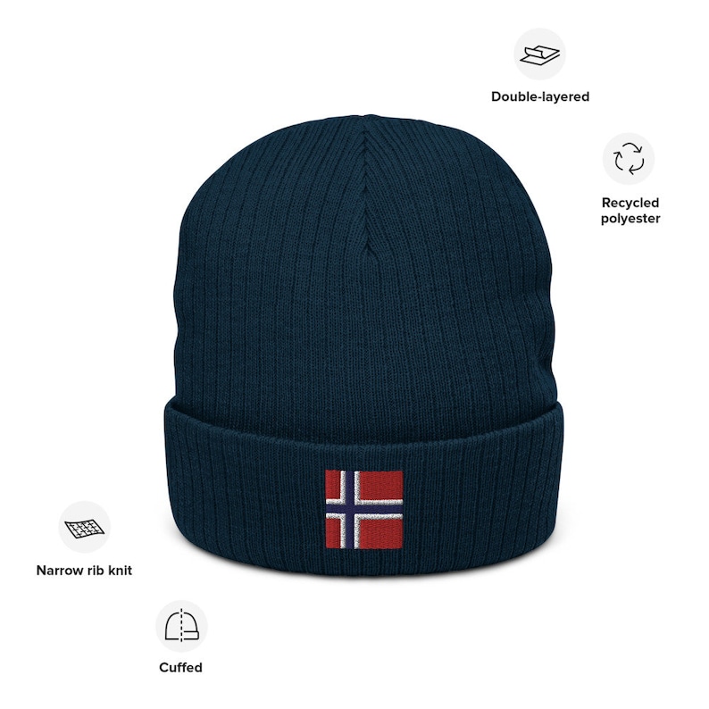 May include: A navy blue knitted beanie with a cuffed brim and a small embroidered Norwegian flag on the front. The beanie is made from recycled polyester and is double-layered for warmth.