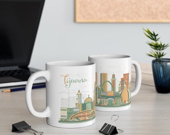 May include: Two white ceramic mugs with a skyline design of Tijuana, Mexico. The mug on the left has the word "Tijuana" written in cursive on the side. Both mugs have a colorful illustration of the city skyline.