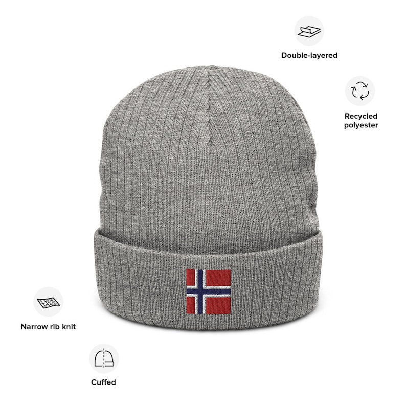 May include: Gray knitted beanie with a cuffed brim and a small embroidered Norwegian flag on the front. The beanie is made from recycled polyester and is double-layered.