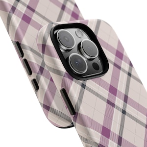 May include: A phone case with a plaid pattern in shades of pink, white, and black. The case has a raised camera bump with a black border.