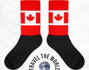 May include: A pair of red and black socks with the Canadian flag on the top of each sock. The socks have the text "TRAVEL THE WORLD" printed on the bottom in a semi-circle around a small globe.
