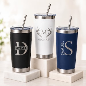 May include: Three stainless steel tumblers with clear lids and metal straws. The black tumbler features the letter D and the name David. The white tumbler displays an antler design with the letter M and name Michael. The blue tumbler shows the letter S and name Samuel.