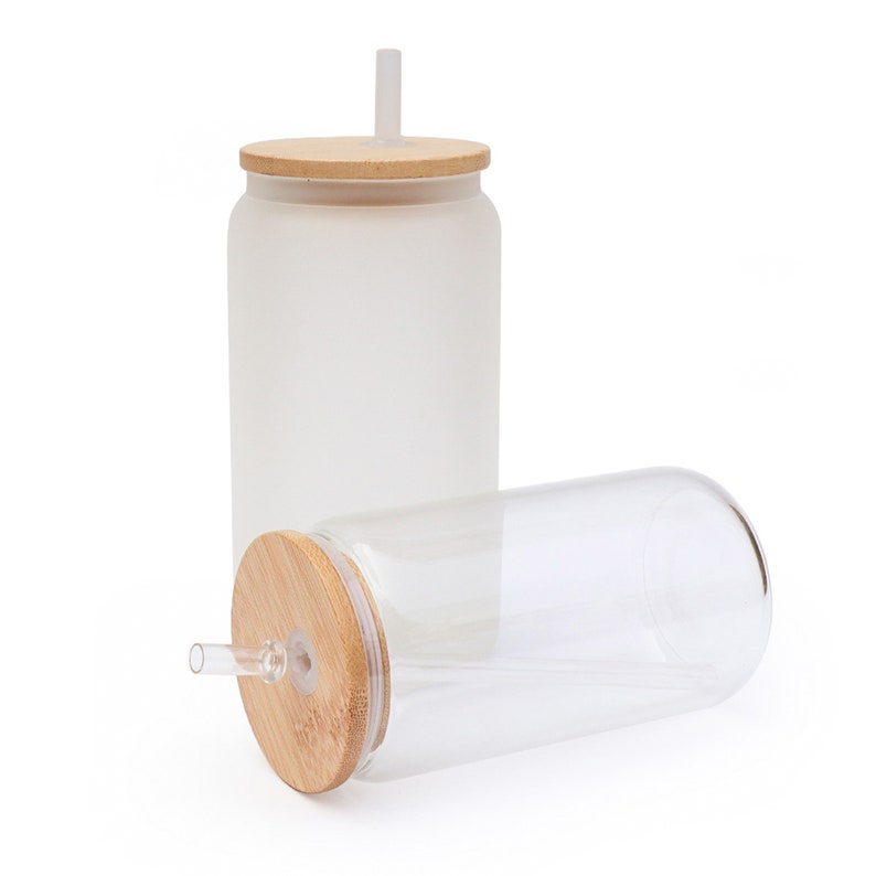 May include: Two glass tumblers with bamboo lids and clear straws. One tumbler is frosted, the other is clear. The tumblers are cylindrical with rounded bottoms, suitable for cold beverages. The lids have a hole for the straw.