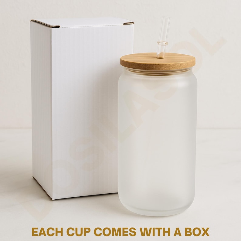 May include: A frosted glass tumbler with a bamboo lid and a clear straw, next to a white cardboard box. The text "EACH CUP COMES WITH A BOX" is printed in gold at the bottom of the image. The tumbler is cylindrical.