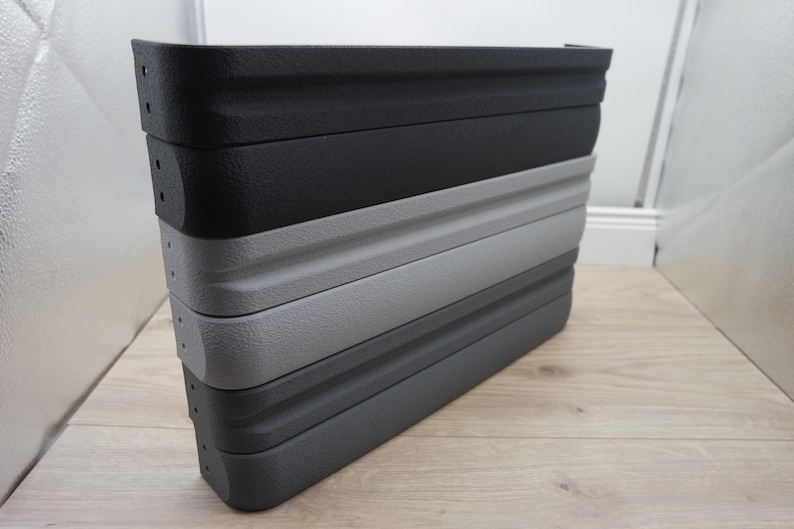 May include: A stack of four collapsible, textured plastic containers in shades of gray and black. The containers are stacked on top of each other, with the top one being black, followed by dark gray, light gray, and a darker gray at the bottom.