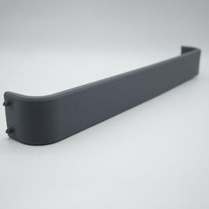 Könnte beinhalten: Ein dunkelgraues, gebogenes, rechteckiges Objekt mit zwei kleinen Vorsprüngen an einem Ende. Das Objekt hat eine glatte, matte Oberfläche, wahrscheinlich aus Kunststoff. Das Design ist einfach und funktional.