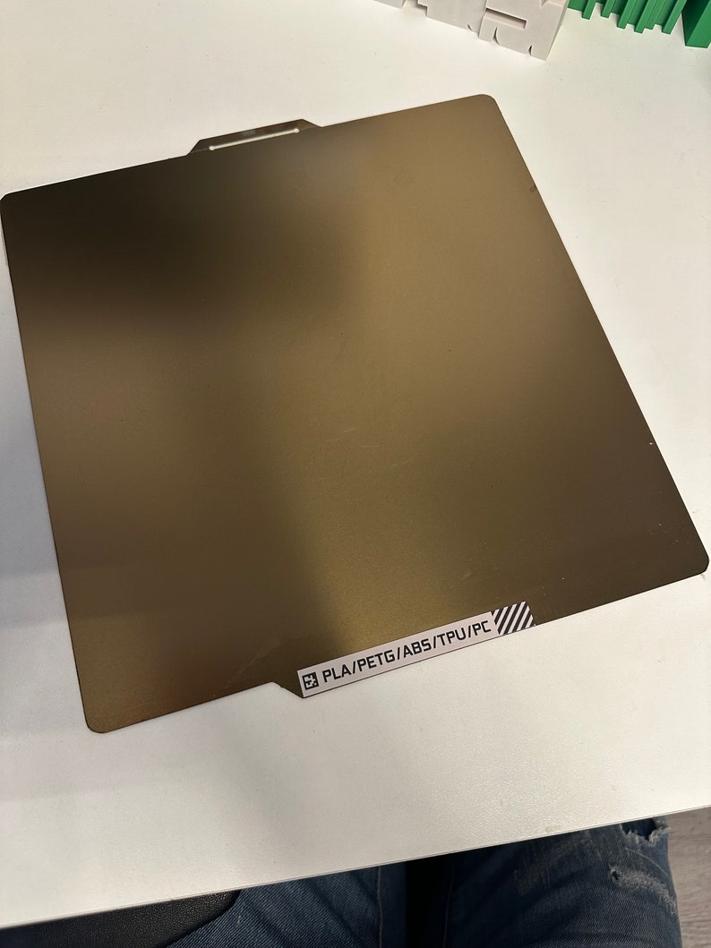 K&ouml;nnte beinhalten: Eine braune Metallplatte mit einem wei&szlig;en Etikett mit der Aufschrift "PLA/PETG/ABS/TPU/PC".