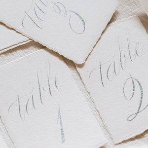 Tabella di nozze Numero d'argento Bordo decorato Carta avorio fatta a mano Calligrafia Numero Reception Elegante decorazione romantica Cena di prova Strappata a mano
