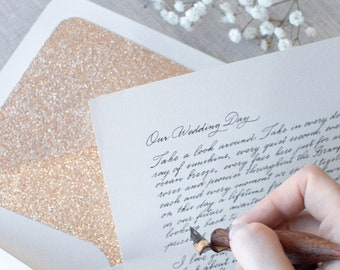以下が含まれることがあります： ページの上部に「Our Wedding Day」と書かれた手書きのレター。レターはエレガントな筆記体で書かれており、ワックスシールで封印されています。レターは、ゴールドのグリッターの裏地が付いた白い封筒の上に置かれています。