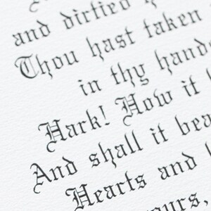 May include: Close-up of a white paper with black gothic script. The text includes phrases like "And dirtied hands" and "Hark! How it". The image is well-lit, highlighting the texture of the paper and the calligraphy.