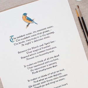 May include: A watercolor print of a poem with a bluebird illustration. The poem is written in elegant calligraphy with a decorative initial letter. Paintbrushes and a paint palette are in the background.