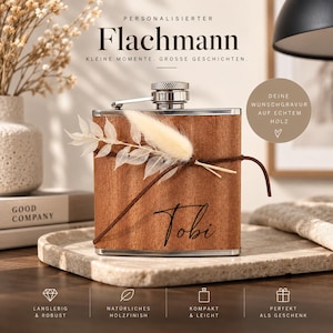 Könnte beinhalten: Ein rechteckiger Metallflachmann mit Holzfurnier-Finish, auf dem der Name Tobi in schwarzer Schreibschrift eingraviert ist. Der Flachmann ist mit einem dekorativen Trockenblumen-Zweig verziert, der mit einer braunen Kordel befestigt ist.