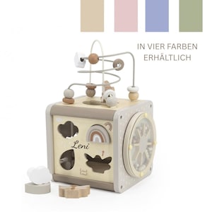 Könnte beinhalten: Ein Holz-Aktivitätswürfel mit einer Perlenbahn, einem Formensortierer und rotierenden Zahnrädern. Der Würfel ist in neutralen Tönen mit einem Regenbogen- und Wolkenmuster bemalt. Der Name "Leni" ist aufgedruckt. Der Text "IN VIER FARBEN ERHÄLTLICH" ist ebenfalls sichtbar.