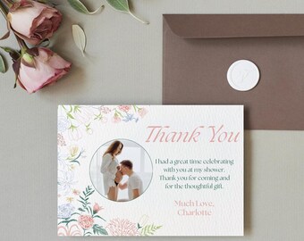 May include: A floral thank you card with a photo of a couple. The card has a pink and blue floral border and the text "Thank You" in pink. The text reads "I had a great time celebrating with you at my shower. Thank you for coming and for the thoughtful gift. Much love, Charlotte."