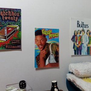 Puede incluir: Miniaturas de carteles de Matchbox Twenty, El Príncipe de Bel-Air y The Beatles se exhiben en una pared blanca. El cartel de Matchbox Twenty presenta un gráfico de caja de cerillas. El cartel de El Príncipe de Bel-Air muestra a Will Smith. El cartel de los Beatles tiene una foto de la banda.