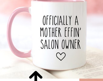 Puede incluir: Una taza de cerámica blanca con asa e interior rosa, que presenta el texto negro 'OFFICIALLY A MOTHER EFFIN' SALON OWNER' y un icono de corazón. La imagen muestra dos opciones de tamaño, 11oz y 15oz, junto a una lista de colores de asa disponibles.