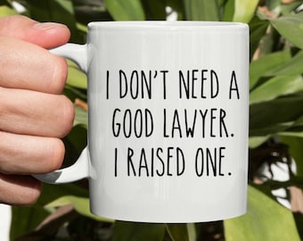 May include: White ceramic coffee mug with black text that reads "I don't need a good lawyer. I raised one."