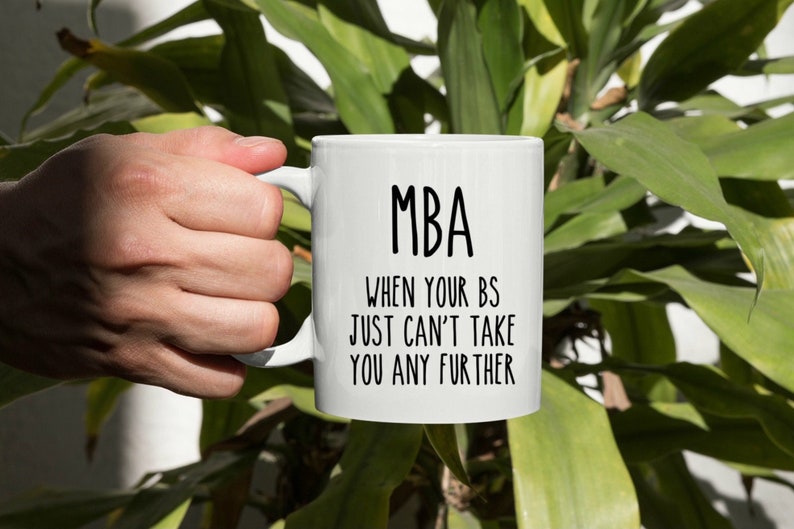 May include: White ceramic coffee mug with black text that reads "MBA When your BS just can't take you any further".