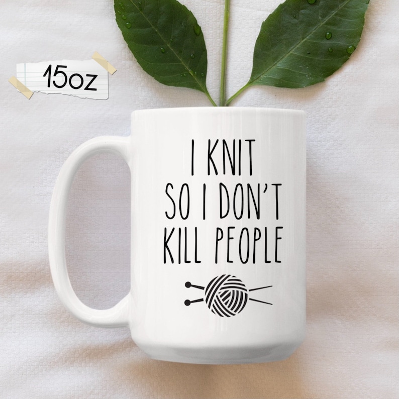 K&ouml;nnte beinhalten: Wei&szlig;e Keramiktasse mit einem schwarzen Design, auf dem "Ich stricke, damit ich keine Leute umbringe" steht. Die Tasse zeigt au&szlig;erdem eine schwarze Illustration einer Wollkn&auml;uel und Stricknadeln.