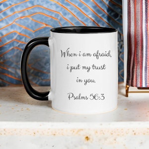 Puede incluir: Taza de caf&eacute; de cer&aacute;mica blanca con asa negra y borde negro. La taza tiene una inscripci&oacute;n negra que dice "Cuando tengo miedo, pongo mi confianza en ti. Salmos 56:3"