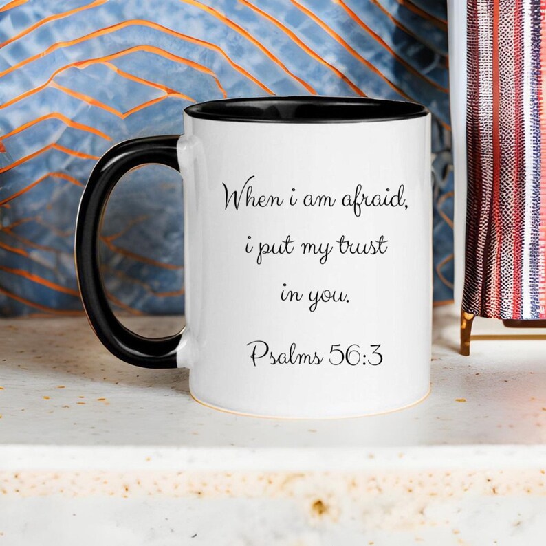 Puede incluir: Taza de caf&eacute; de cer&aacute;mica blanca con asa negra y borde negro. La taza tiene una inscripci&oacute;n negra que dice "Cuando tengo miedo, pongo mi confianza en ti. Salmos 56:3"