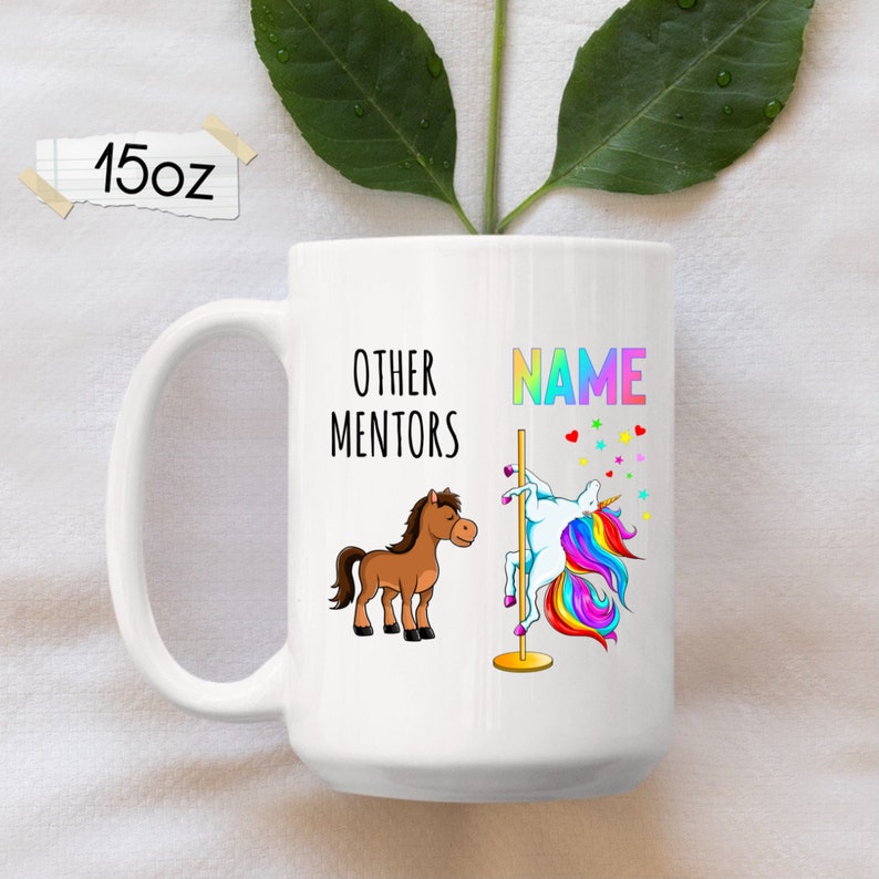 May include: White ceramic mug featuring a brown horse and a rainbow unicorn on a pole. The text on the mug reads "Other Mentors" and "NAME".