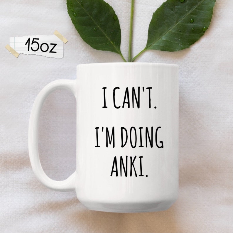 May include: White ceramic coffee mug with a black inscription that reads "I can't. I'm doing Anki."
