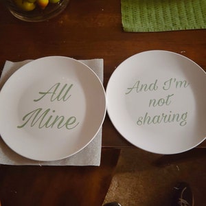 May include: Two white plates with green text. The plate on the left says "All Mine". The plate on the right says "And I'm not sharing".