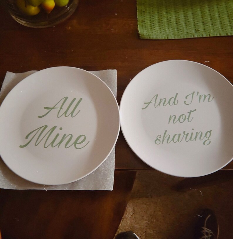 May include: Two white plates with green text. The plate on the left says "All Mine". The plate on the right says "And I'm not sharing".