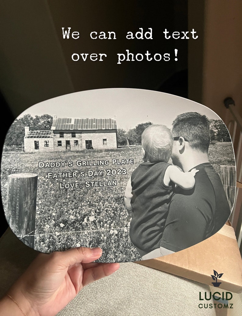 May include: An oval-shaped plate featuring a black and white photograph of a person holding a child in front of a house. The text on the plate reads: DADDY'S GRILLING PLATE, FATHER'S DAY 2023, LOVE, STELLAN. The top of the image includes the text: We can add text over photos!