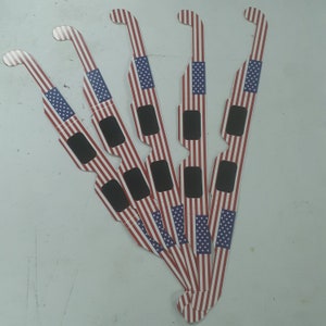 May include: Six red, white and blue cardboard 3D glasses with black lenses. The glasses are decorated with an American flag pattern.