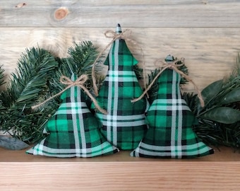 May include: Three green and white plaid fabric Christmas tree ornaments with brown twine bows.