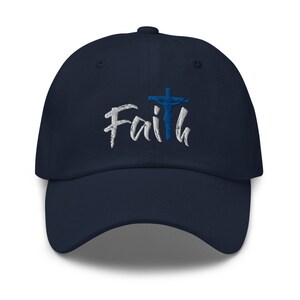 May include: A navy blue baseball cap with the word "Faith" embroidered in white with a blue cross and a figure of Jesus on the cross.