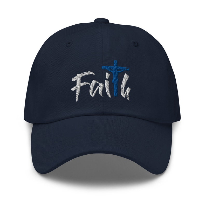 May include: A navy blue baseball cap with the word "Faith" embroidered in white with a blue cross and a figure of Jesus on the cross.