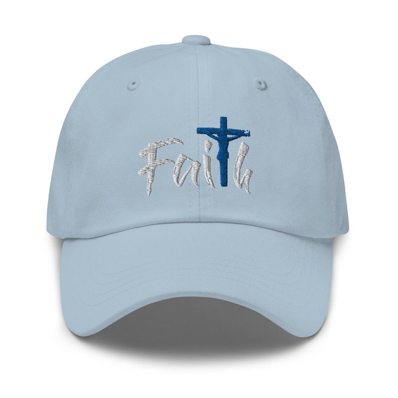 May include: A light blue baseball cap with an embroidered design of a cross with a figure on it and the word "Faith" in white lettering.