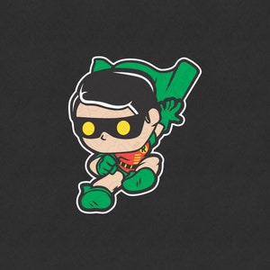 Op de afbeelding: Een cartoonillustratie van Robin, een superheld uit het DC Comics-universum. Hij draagt ​​een groen en rood kostuum met een geel masker en een cape. Hij zit in een gehurkte positie met gekruiste armen.