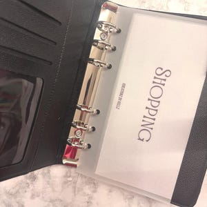 May include: A white ceramic mug with a black handle and the text "But first, coffee" in a handwritten style. The mug is on a white surface. The mug is likely for hot beverages.