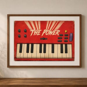 May include: A framed wall art print featuring a red synthesizer illustration with white light rays emanating from the center. The text THE POWER is printed in white above the keyboard, which has black and white keys, knobs, and buttons.