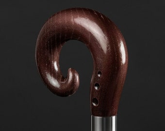 May include: A dark brown wooden walking stick with a curved handle and a silver band. The handle has a unique design with a small loop at the top.