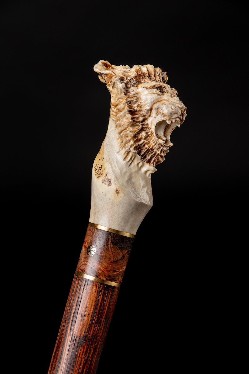 Puede incluir: Un bast&oacute;n con un mango tallado en forma de cabeza de le&oacute;n hecho de hueso. El mango es de color crema claro con marcas marrones. El bast&oacute;n est&aacute; hecho de madera oscura con una banda de lat&oacute;n.