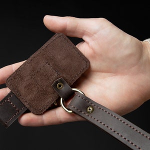 May include: A brown leather key chain with a suede key holder. The key holder has a stitched flap and a metal ring.