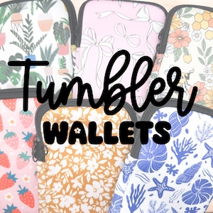 May include: A collection of colorful zippered pouches with various floral and geometric patterns. The pouches are labeled "Tumbler Wallets".