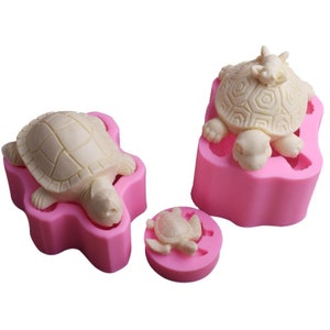 May include: Three pink silicone moulds for making turtle-shaped treats. The moulds are in different sizes and feature detailed turtle designs.