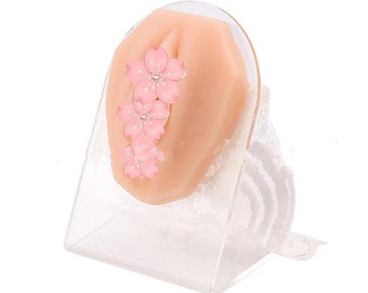 May include: A clear plastic stand with a white lace base holds a pink silicone model with a design of pink cherry blossoms.