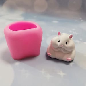 May include: Pink silicone mould shaped like a small pot, and a white silicone mould shaped like a hamster.