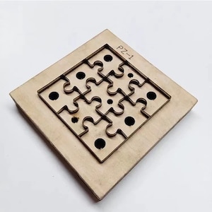 Può includere: Un modello di fustellatura in legno con un design a puzzle e otto tagli circolari. Il modello è etichettato "PZ-1".