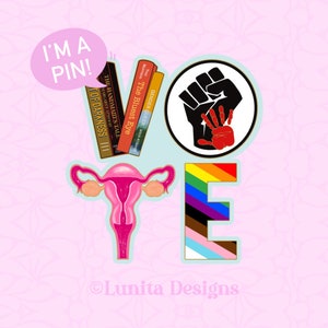 Può includere: Un adesivo colorato con la parola "VOTE" in grandi lettere. Le lettere sono composte da strisce di diversi colori, tra cui arcobaleno, bianco e nero, e rosa e blu. L'adesivo presenta anche un pugno chiuso con una mano più piccola all'interno, un utero e una pila di libri con titoli come "The Bluest Eye" e "The Handmaid's Tale". L'adesivo ha un fumetto sopra che dice "I'm a pin!"