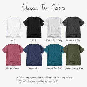a collection of classic t-shirt colors, including white, black, light gray, dark gray, maroon, navy, deep teal, and military green. The colors may appear slightly different due to screen settings, and not all colors are available in every style.
