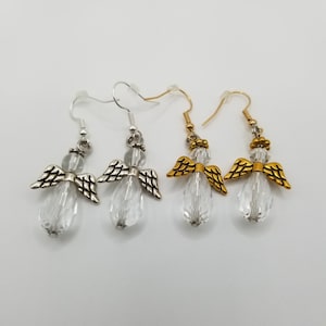 May include: A pair of silver angel earrings and a pair of gold angel earrings. Each earring features a clear crystal teardrop with silver or gold angel wings.